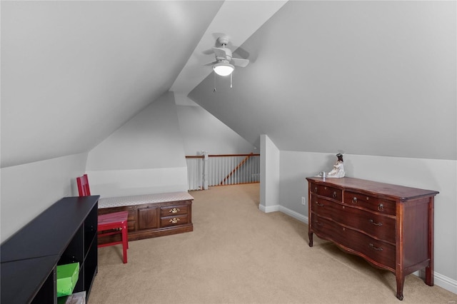 interior space featuring a ceiling fan, light colored carpet, vaulted ceiling, and baseboards