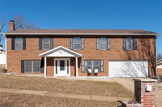 view of front of property featuring a garage, driveway, brick siding, and a chimney