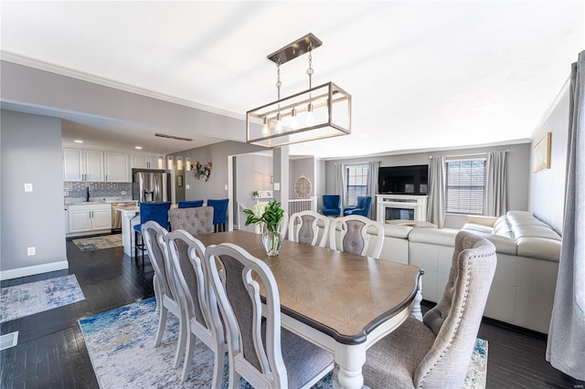 dining space with a notable chandelier, crown molding, baseboards, and dark wood-style flooring