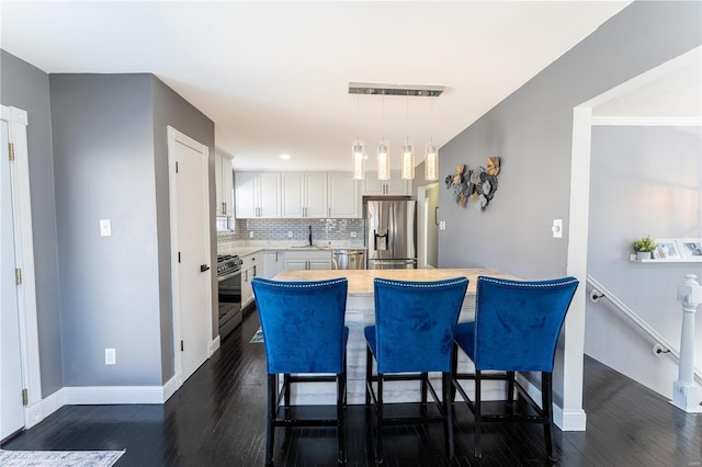 kitchen with stainless steel appliances, tasteful backsplash, light countertops, white cabinets, and a sink