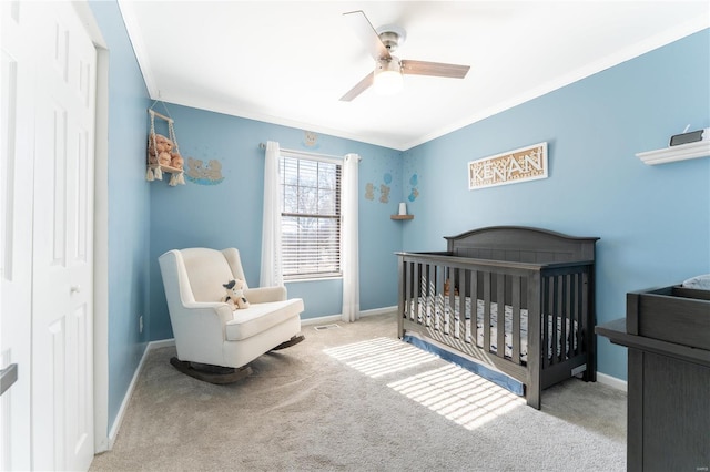 bedroom with ornamental molding, a crib, carpet, and baseboards