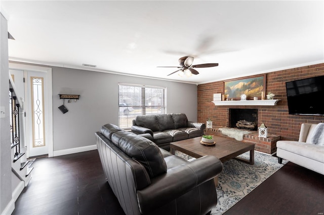 living area with dark wood-style floors, visible vents, a brick fireplace, ceiling fan, and baseboards