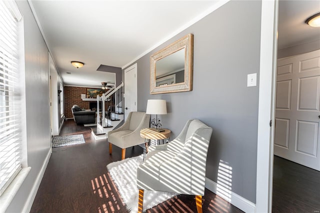 hall with brick wall, stairway, wood finished floors, and baseboards