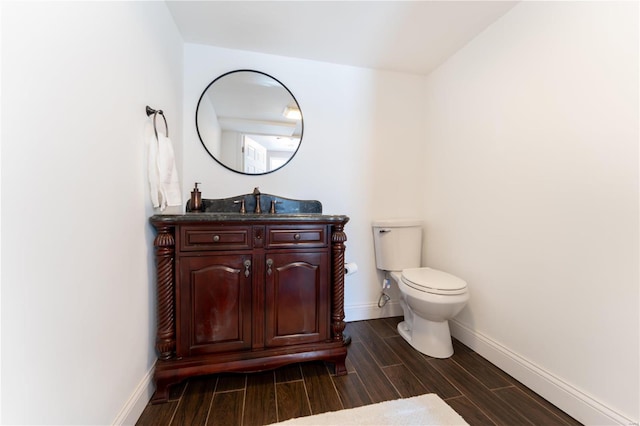 bathroom featuring wood finish floors, vanity, toilet, and baseboards