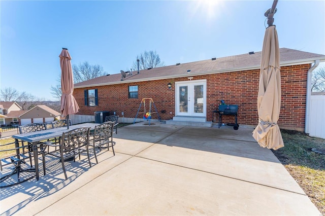 rear view of property featuring a patio area, french doors, brick siding, and fence