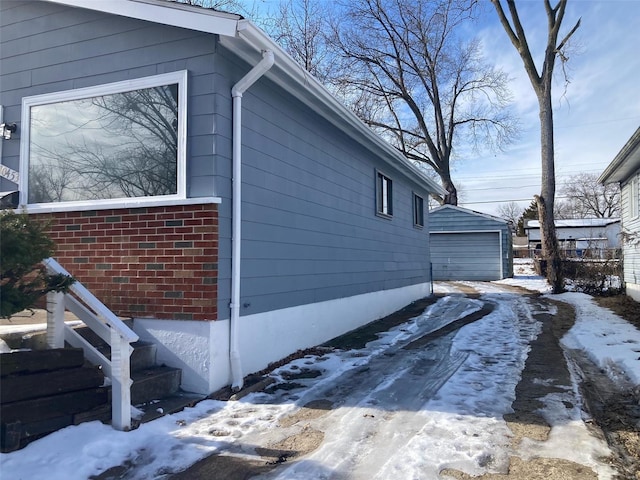 view of snow covered exterior featuring a garage and an outdoor structure