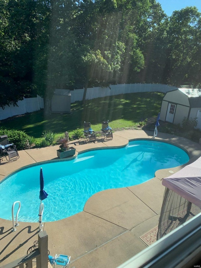 view of pool with a lawn, a patio, a fenced backyard, a storage unit, and an outdoor structure