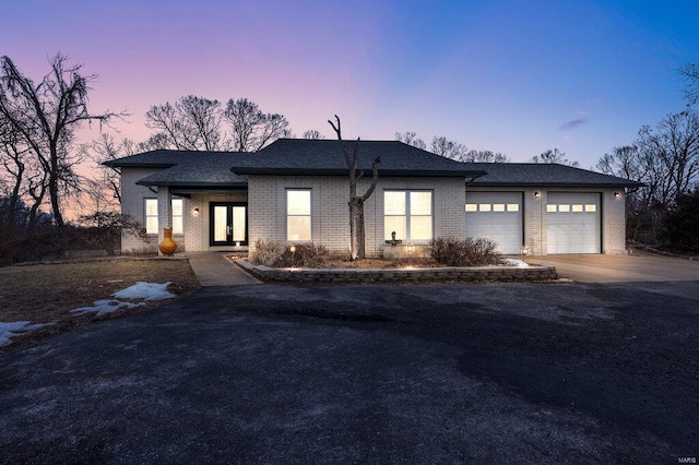 view of front facade featuring aphalt driveway, brick siding, a garage, and roof with shingles