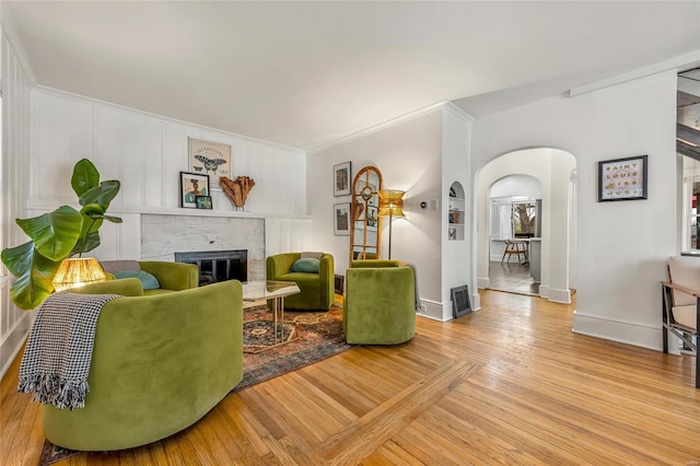 living room featuring crown molding, a brick fireplace, and light hardwood / wood-style flooring