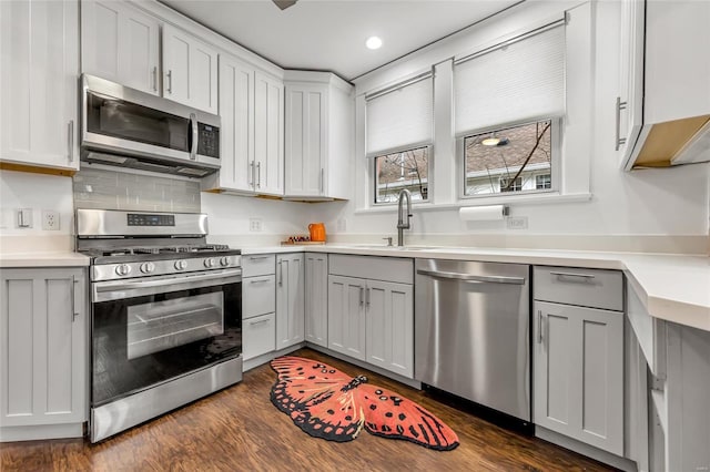 kitchen with sink, dark wood-type flooring, gray cabinetry, stainless steel appliances, and decorative backsplash