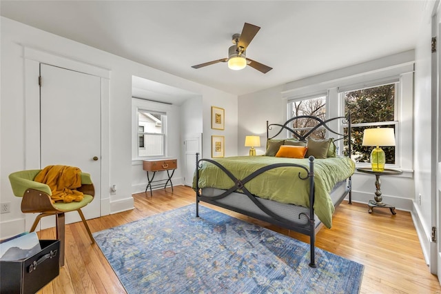 bedroom with multiple windows, ceiling fan, and light hardwood / wood-style floors