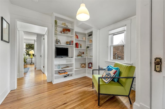 living area with built in shelves and light hardwood / wood-style floors