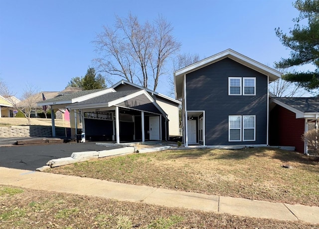 traditional-style home with driveway, a carport, and a front yard