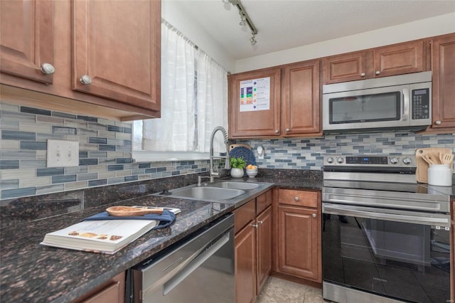 kitchen with stainless steel appliances, brown cabinets, a sink, and tasteful backsplash