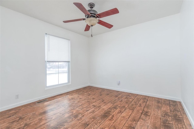 spare room featuring baseboards, visible vents, ceiling fan, and wood finished floors