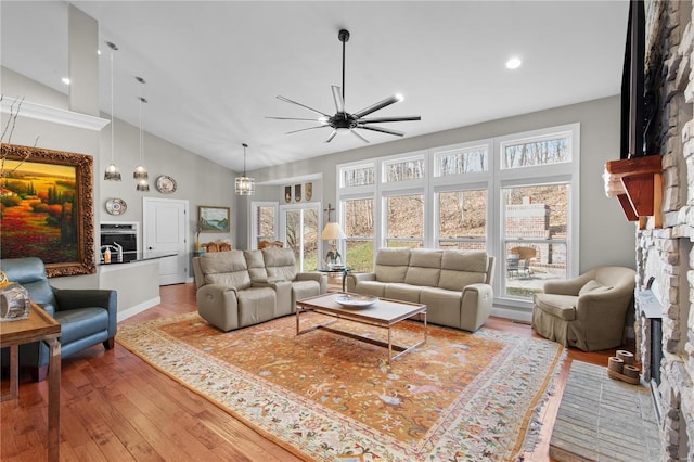 living room with hardwood / wood-style flooring, ceiling fan, high vaulted ceiling, and a fireplace