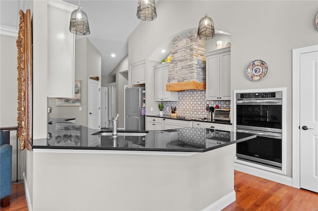 kitchen with appliances with stainless steel finishes, kitchen peninsula, and hanging light fixtures