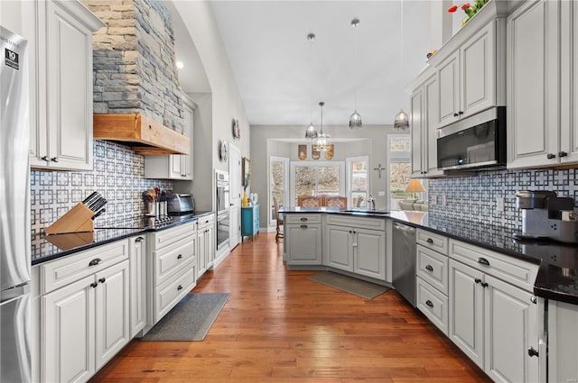 kitchen featuring white cabinetry, stainless steel appliances, kitchen peninsula, and light hardwood / wood-style flooring