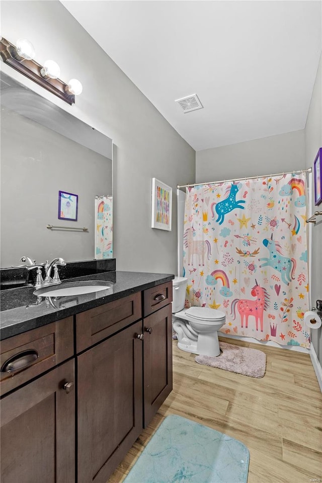 bathroom with hardwood / wood-style flooring, vanity, toilet, and curtained shower