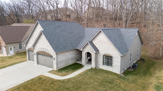 french provincial home with a garage, central air condition unit, and a front lawn