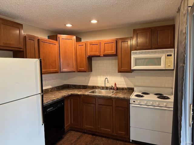 kitchen with white appliances, dark countertops, brown cabinets, a sink, and backsplash