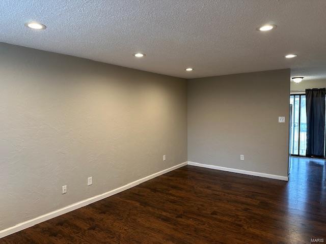 empty room featuring dark wood-type flooring, recessed lighting, a textured ceiling, and baseboards