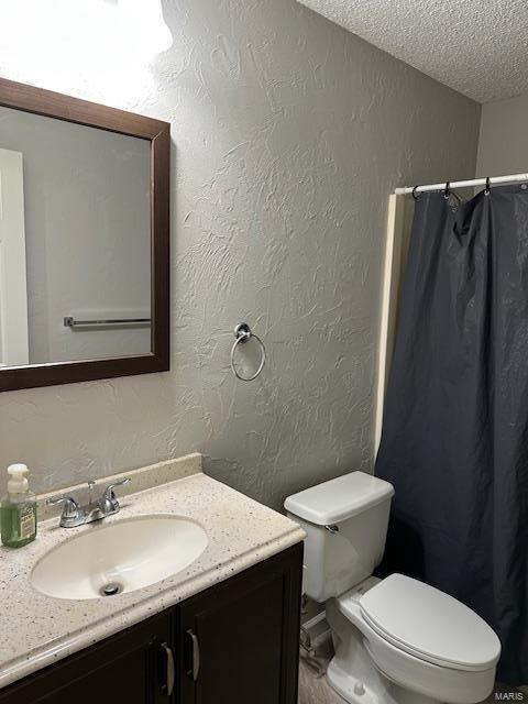 full bathroom with toilet, a textured wall, a textured ceiling, and vanity