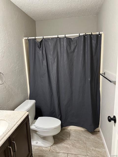 bathroom featuring toilet, vanity, a textured ceiling, and a textured wall