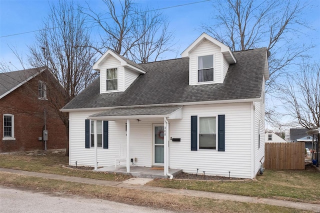 cape cod home featuring a porch, a front yard, fence, and a shingled roof