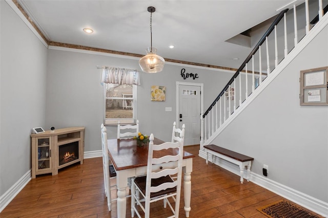 dining room with ornamental molding, hardwood / wood-style flooring, baseboards, and stairs