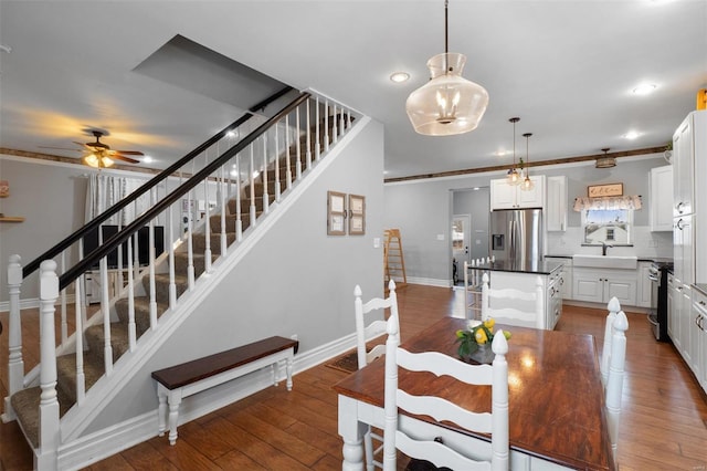 dining space featuring stairs, wood-type flooring, a ceiling fan, and baseboards