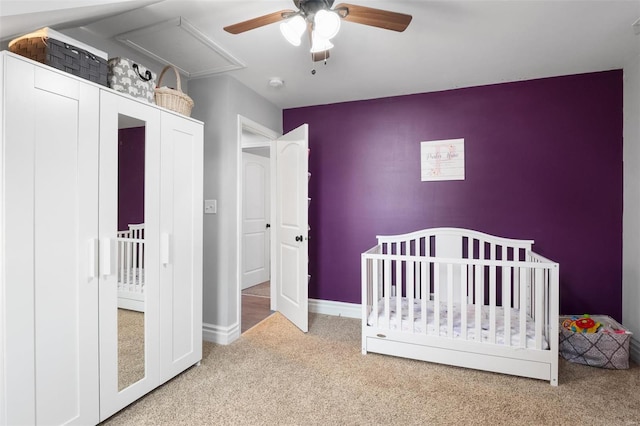 bedroom featuring a crib, ceiling fan, baseboards, and carpet flooring