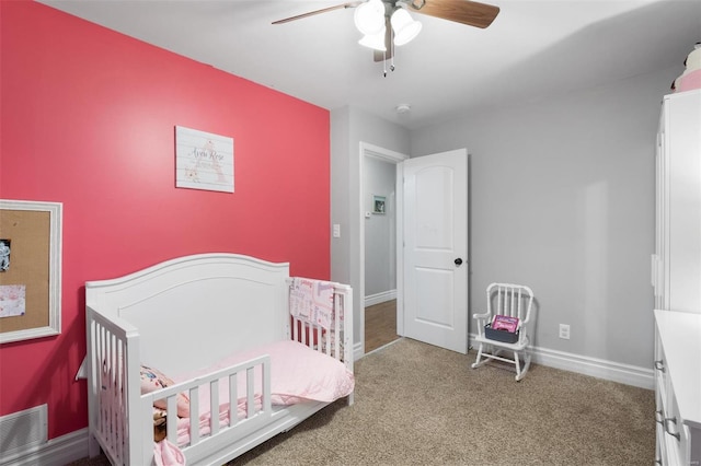 bedroom featuring carpet floors, a crib, visible vents, and baseboards