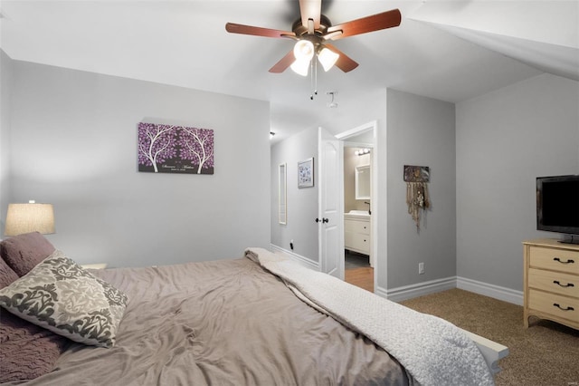 carpeted bedroom featuring lofted ceiling, connected bathroom, baseboards, and ceiling fan