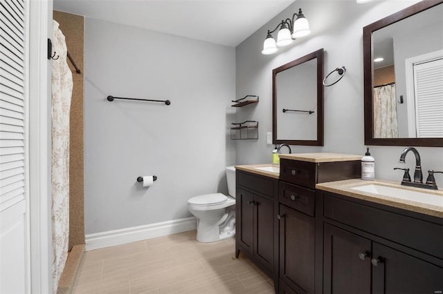 full bathroom with double vanity, a sink, toilet, and baseboards