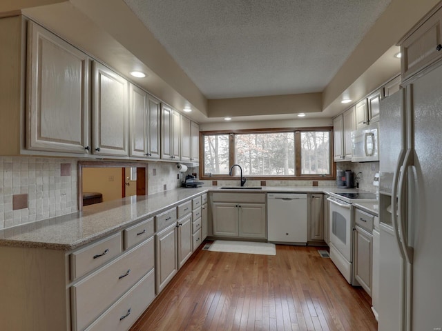 kitchen with sink, kitchen peninsula, white appliances, light hardwood / wood-style floors, and backsplash