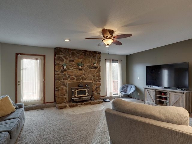 carpeted living room featuring ceiling fan, a textured ceiling, and a wood stove