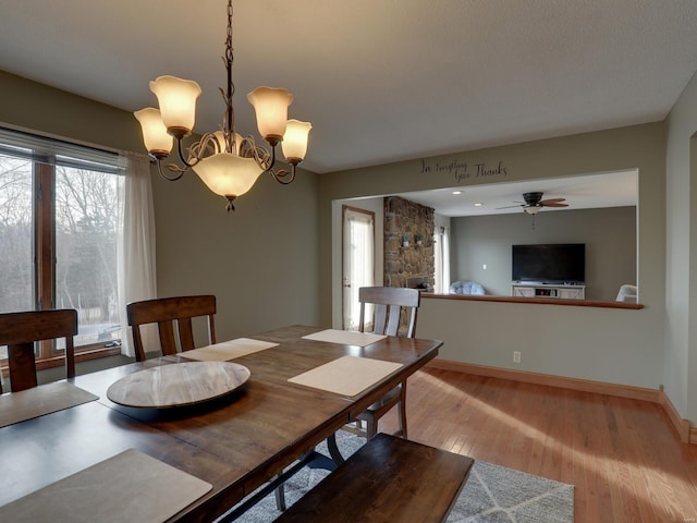 dining space featuring ceiling fan with notable chandelier and light wood-type flooring