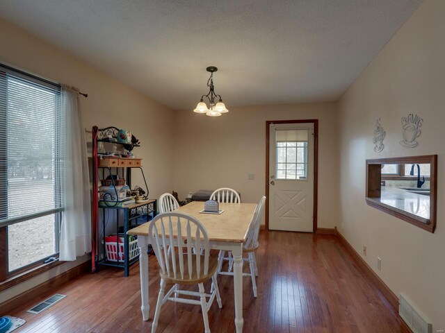 dining space with hardwood / wood-style floors, a textured ceiling, and a chandelier