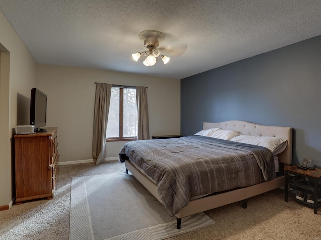 carpeted bedroom featuring ceiling fan and a textured ceiling