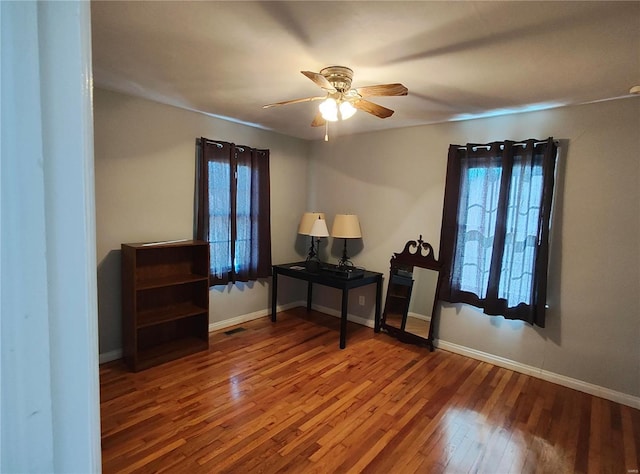 interior space featuring wood-type flooring, visible vents, baseboards, and ceiling fan