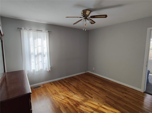 unfurnished room featuring a ceiling fan, wood-type flooring, visible vents, and baseboards