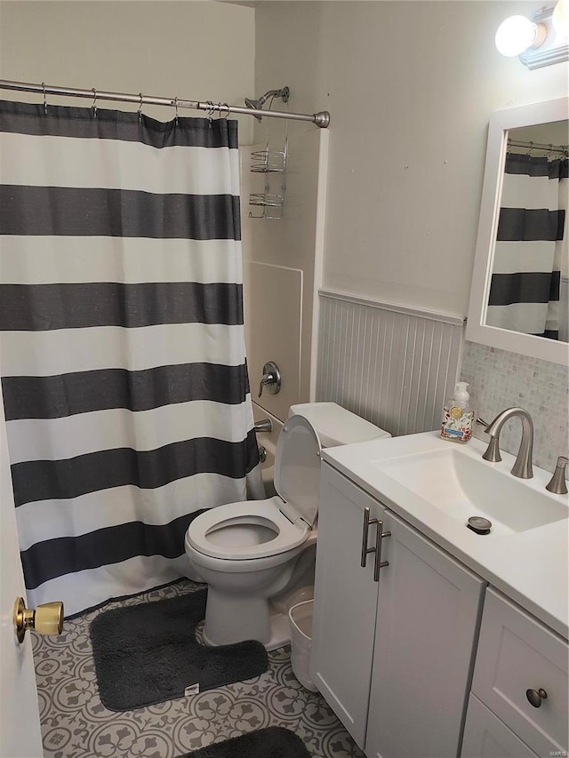 bathroom with toilet, a shower with shower curtain, vanity, wainscoting, and tile patterned floors