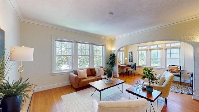 living room featuring arched walkways, a textured ceiling, a healthy amount of sunlight, and wood finished floors