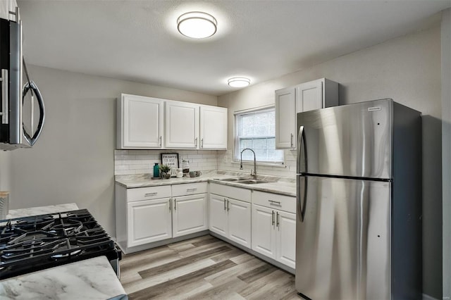 kitchen featuring white cabinetry, stainless steel appliances, sink, and tasteful backsplash