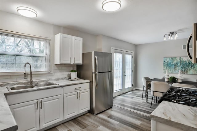 kitchen featuring french doors, sink, tasteful backsplash, stainless steel fridge, and white cabinets