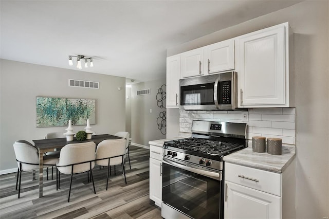 kitchen with tasteful backsplash, white cabinets, and appliances with stainless steel finishes