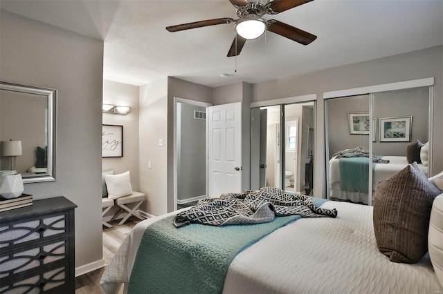 bedroom featuring multiple closets, wood-type flooring, ensuite bathroom, and ceiling fan