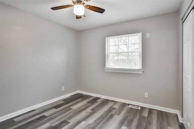 unfurnished bedroom featuring a closet, dark hardwood / wood-style floors, and ceiling fan