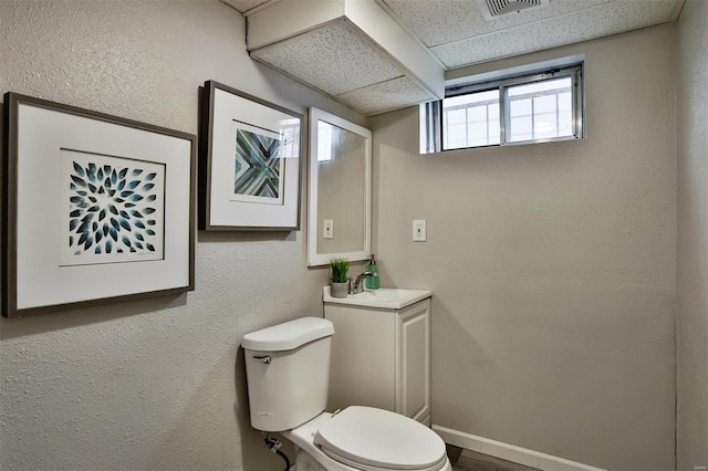 bathroom featuring vanity, toilet, and a drop ceiling